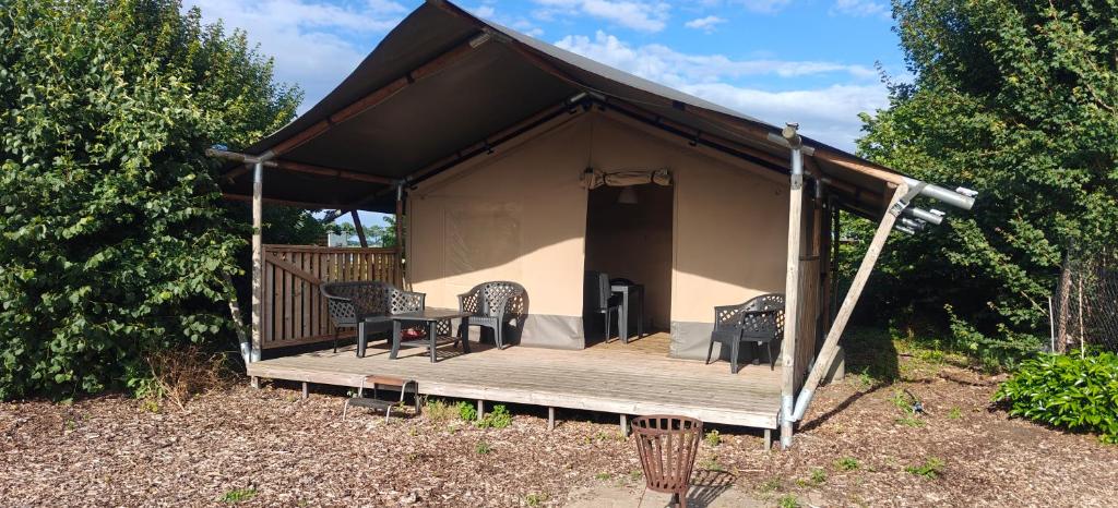 a house with a deck with a table and chairs at Camping Amable in Someren