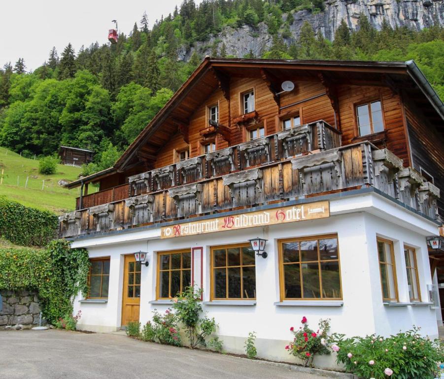 a building with a balcony on top of it at Hotel Restaurant Waldrand in Isenfluh