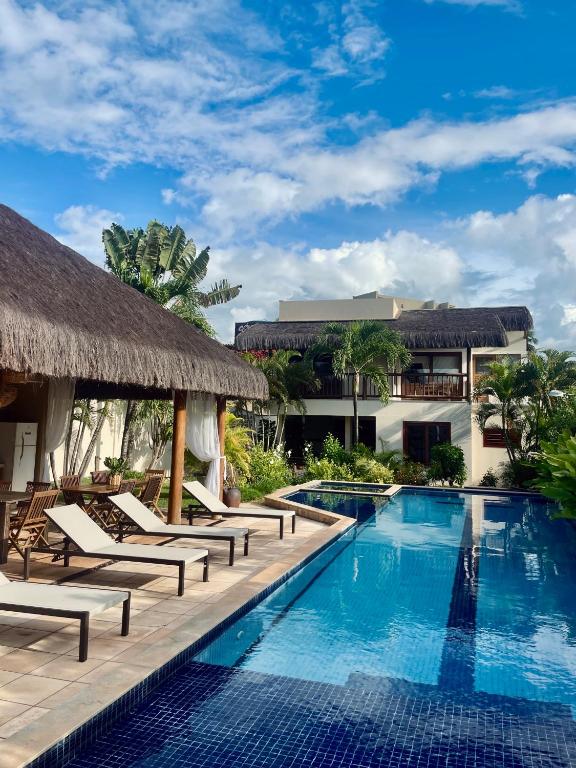 a swimming pool with chaise lounge chairs and a resort at Mareias Villas in São Miguel do Gostoso