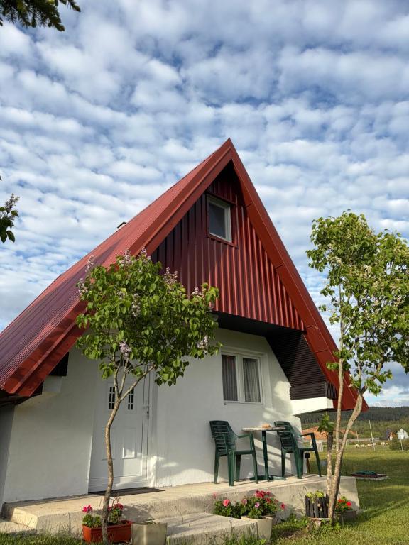 a house with a red roof and some chairs at Soko Guest House in Žabljak