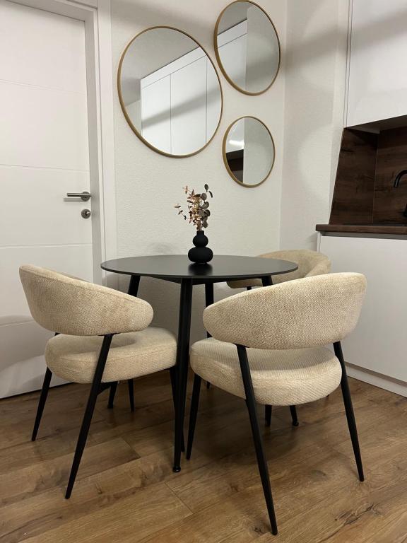 a dining room table with two chairs and two mirrors at Apartman Rawda in Jajce