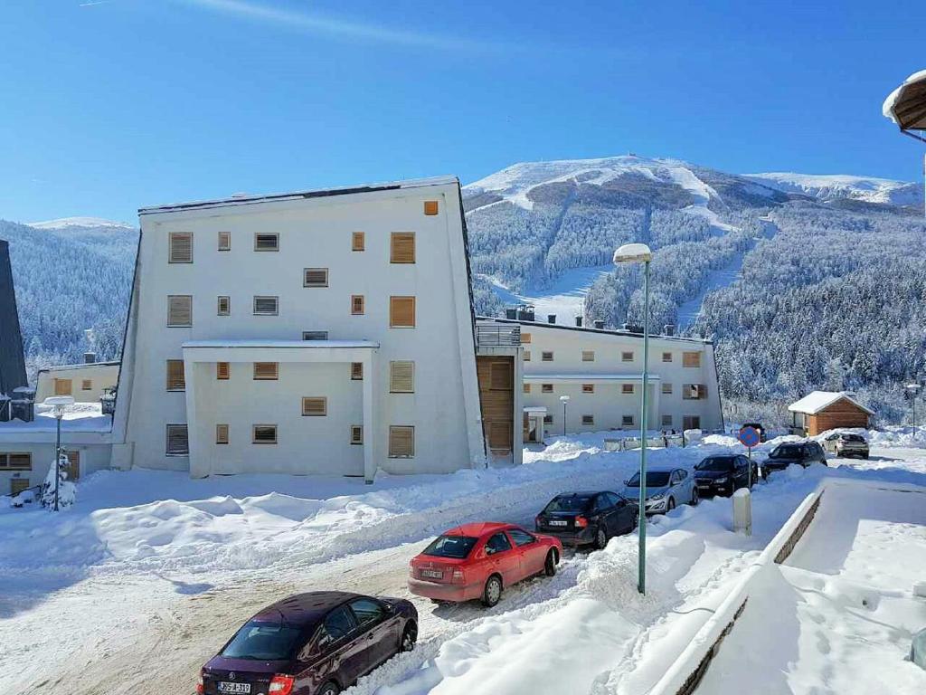 a group of cars parked in the snow in front of a building at Apartment Hobbit - Bjelašnica in Bjelašnica