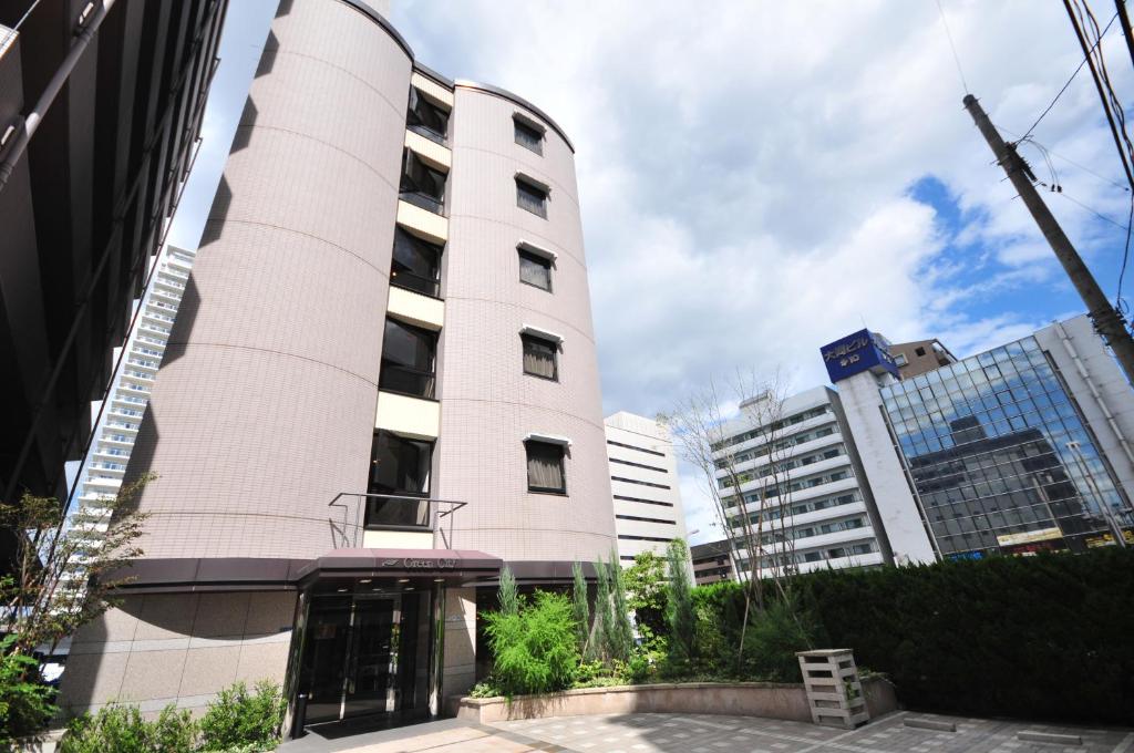 a pink building in front of some buildings at Hotel Green City in Sendai