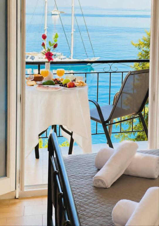 a table with food on a balcony with a view of the ocean at Aether seaview in Benitses