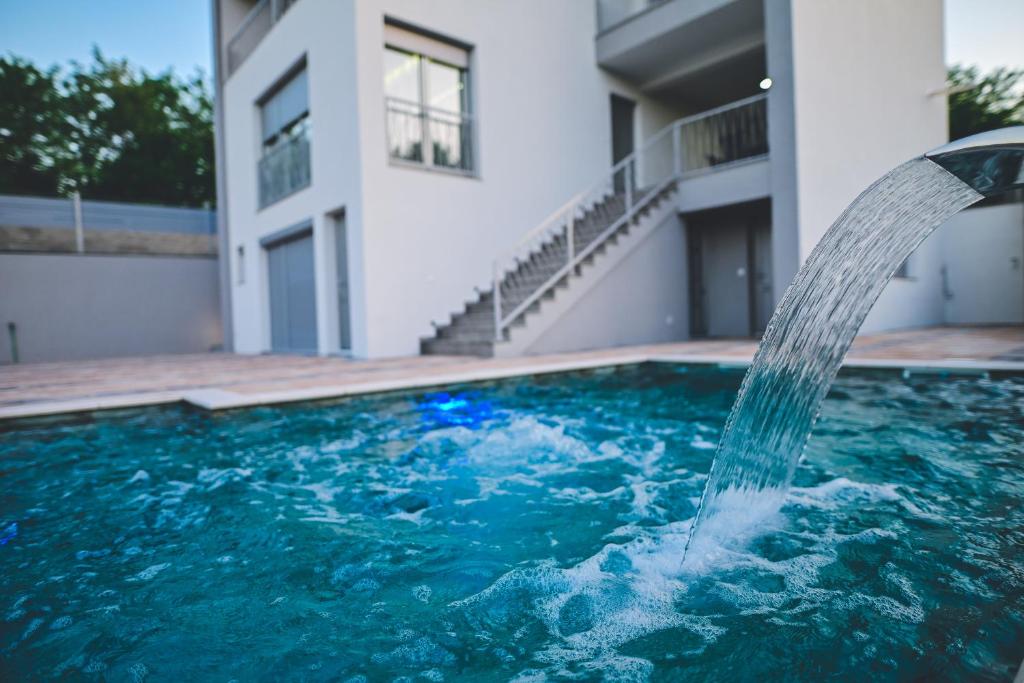 a pool with a water fountain in front of a building at Villa Dubrava in Matuzići