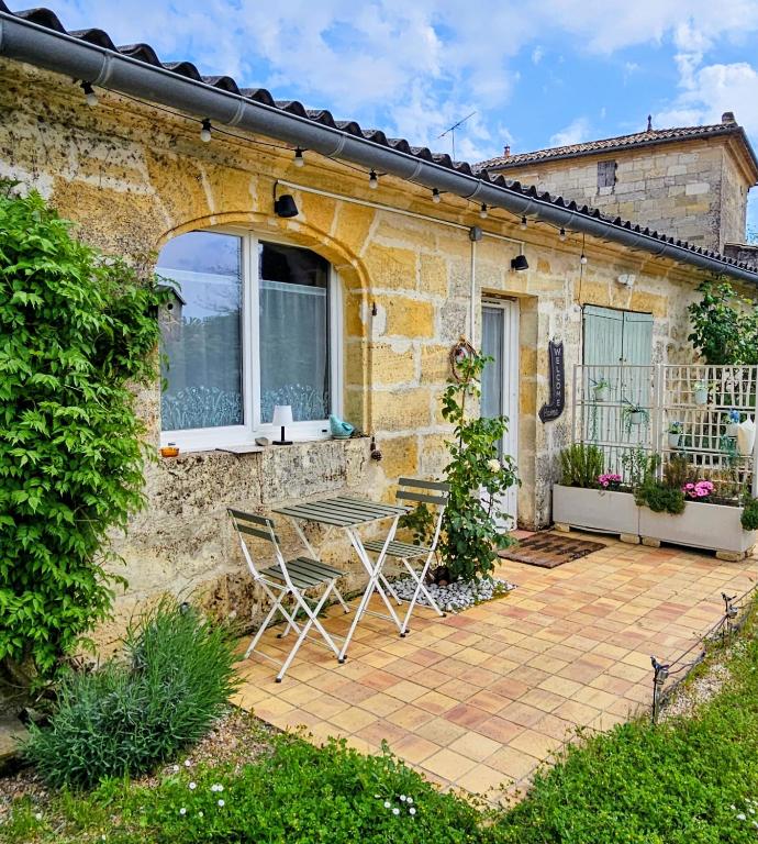 a patio with a table and chairs in front of a house at Maison Finchette pour 2 - 5 min Saint-Émilion - Terrasse privée - Parking - Arrivée autonome in Sainte-Terre