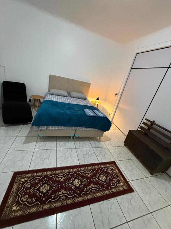 a bedroom with a bed and a chair and a rug at Kitnets Kretzer Hinckel 3 - CENTRO in Alfredo Wagner