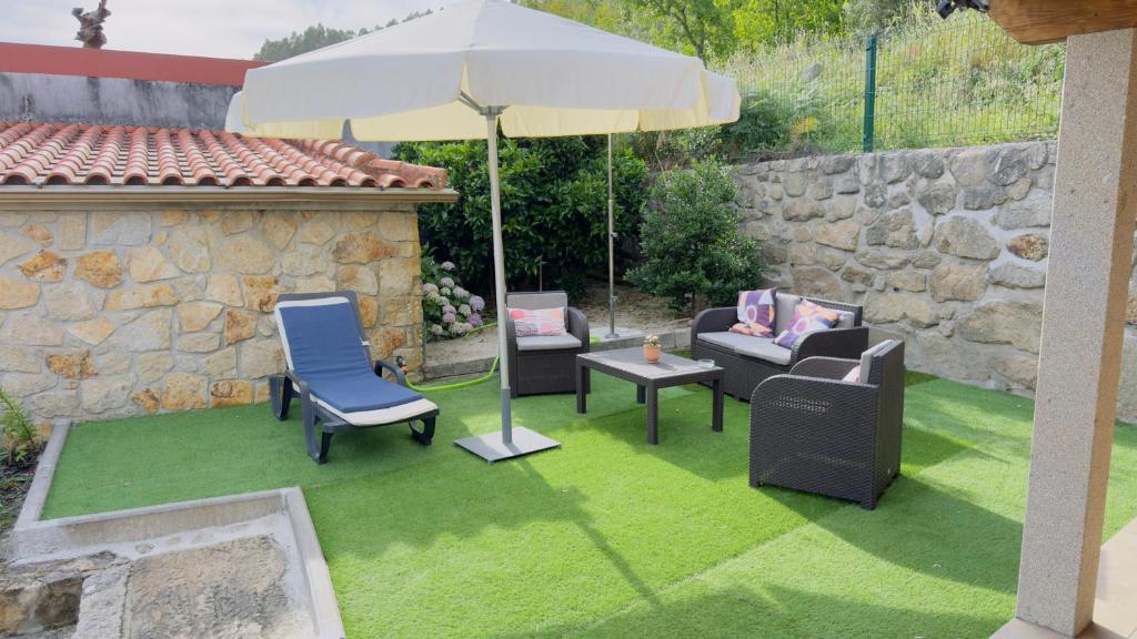 a patio with chairs and an umbrella on grass at Casa dos Devezas in São Gregório