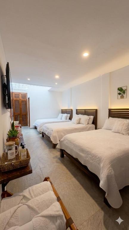 a room with three beds and a television in it at La Toscana Hostel in Villa de Leyva