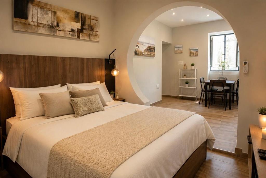 a bedroom with a large bed and a dining room at Sliema Arch Suites Modern Boutique Apartment in St. Julianʼs