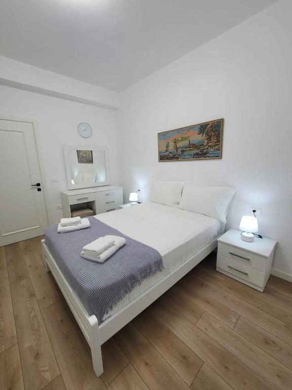 a white bedroom with a bed with two towels on it at Vila Mollanji in Tirana