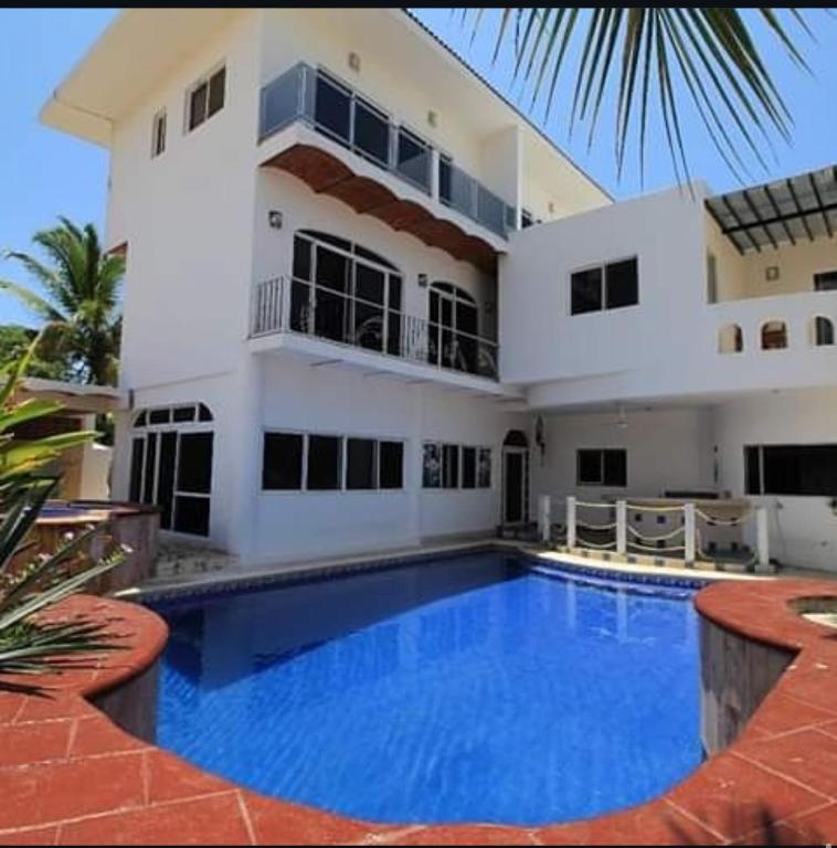 a house with a large swimming pool in front of it at Mar Real Suites Guayabitos in Rincon de Guayabitos