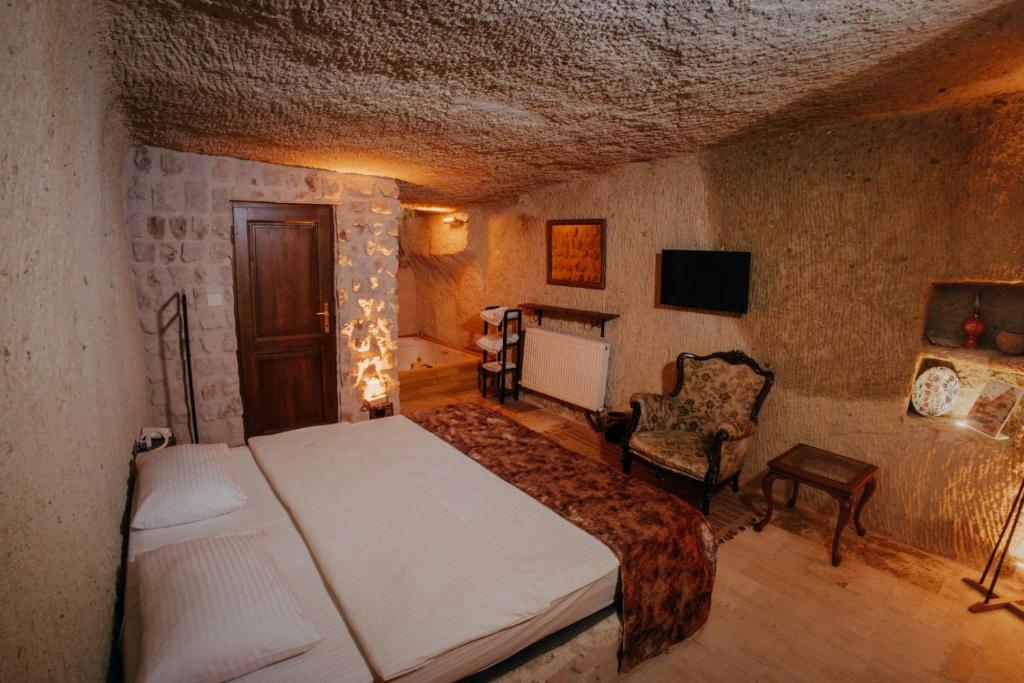 a bedroom with a bed and a chair in a room at Saliche Cave Suite in Nevşehir