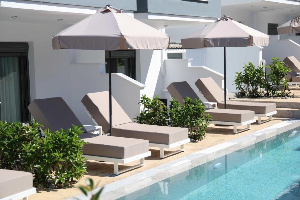 a row of lounge chairs and umbrellas next to a swimming pool at Akritas Hotel Pefkochori in Pefkochori
