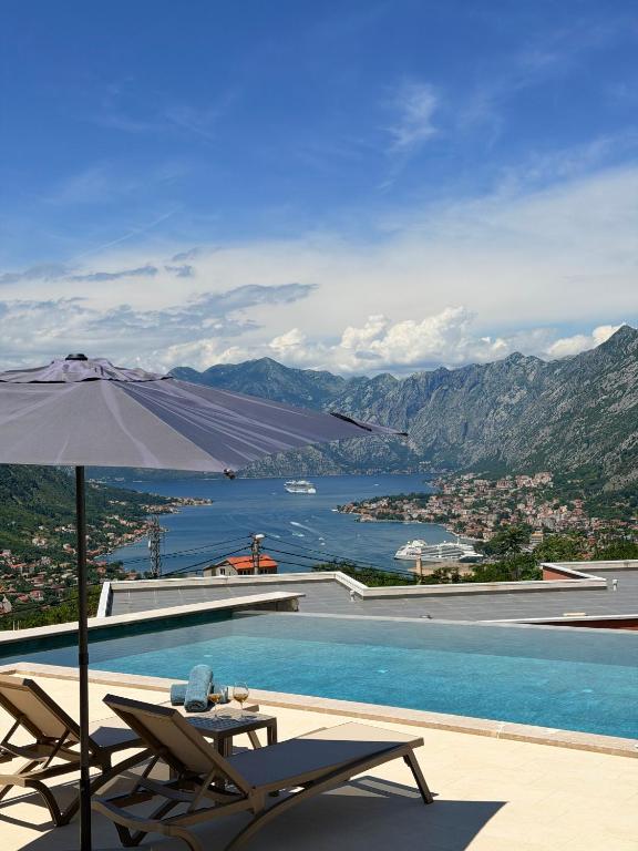 a swimming pool with two chairs and an umbrella at Azure Boka in Trojica