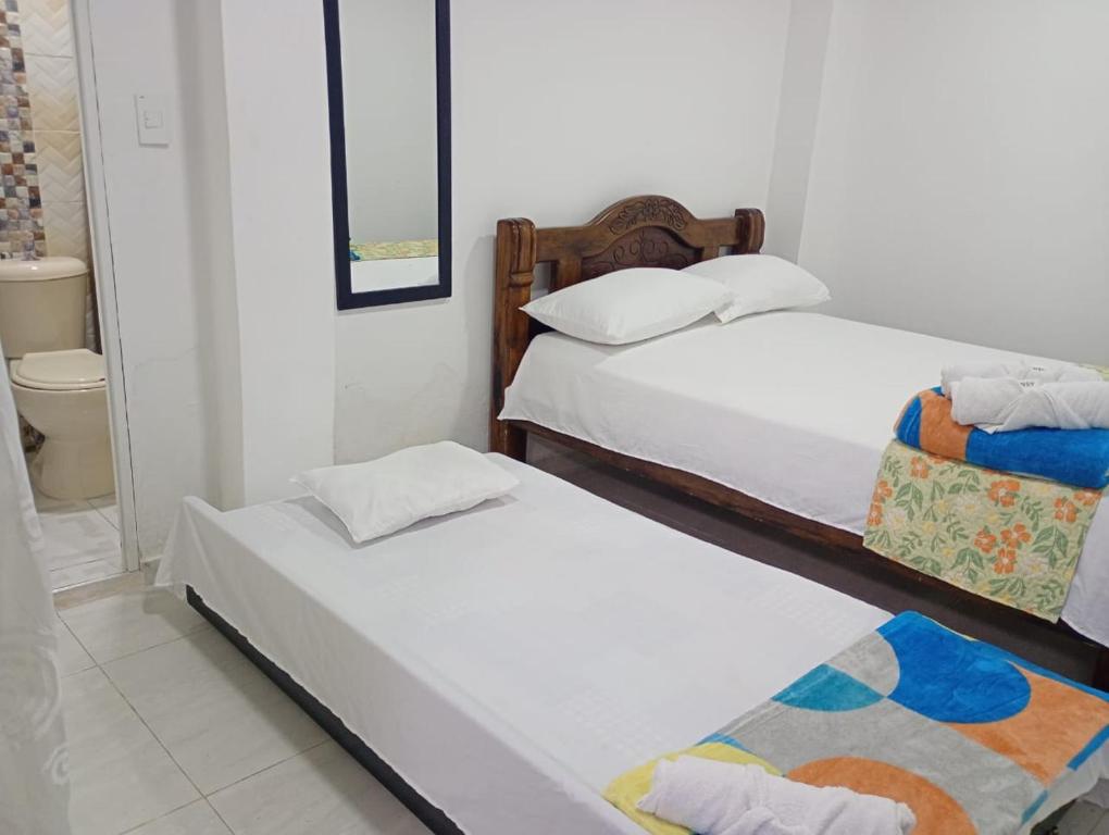 a bedroom with two beds and a mirror at Casa Hotel Bijaos in Mompós