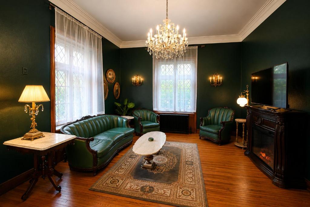 a living room with green furniture and a chandelier at Winston Churchill - le charme Tudor au cœur de Sherbrooke in Sherbrooke