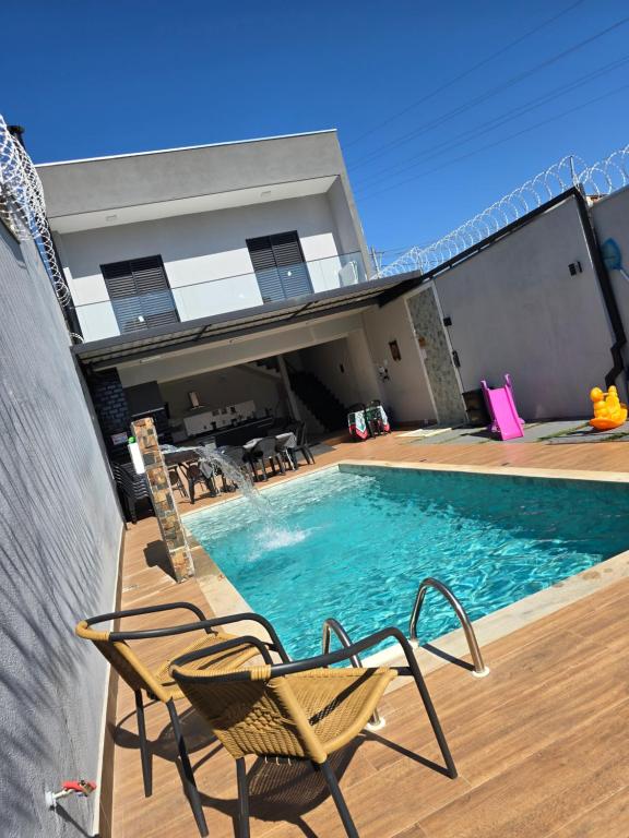a swimming pool with chairs and a house at Sobrado novo e lindo com piscina in São José dos Campos