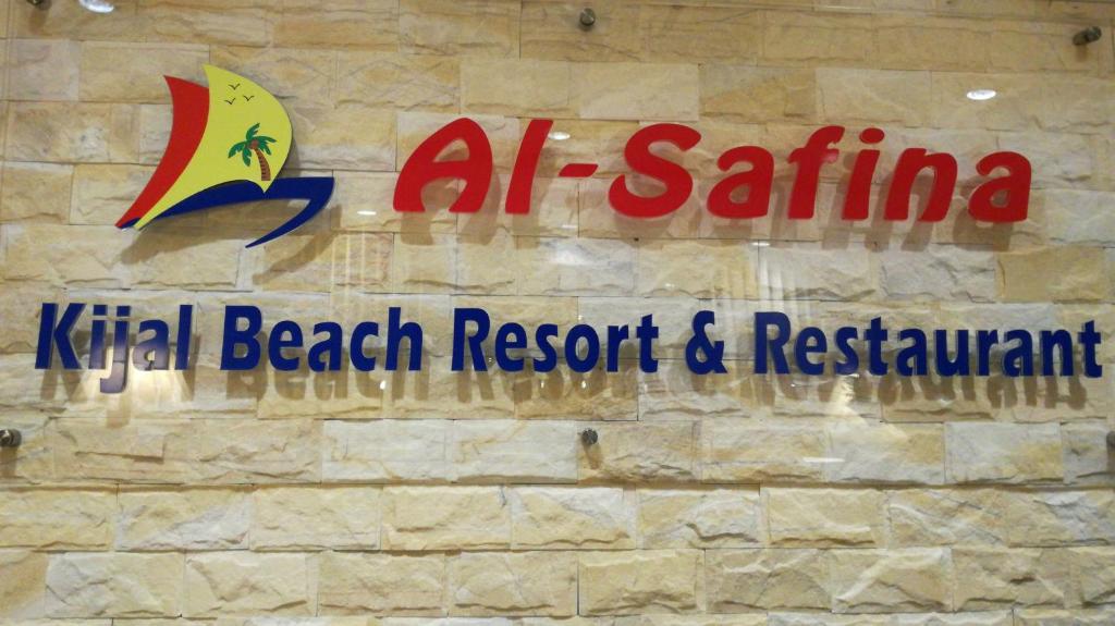 a sign for a beach resort and restaurant on a stone wall at Al Safina Kijal Beach Resort in Kijal