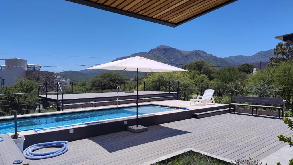 a swimming pool with an umbrella and a deck at Trovare un Senso in Capilla del Monte