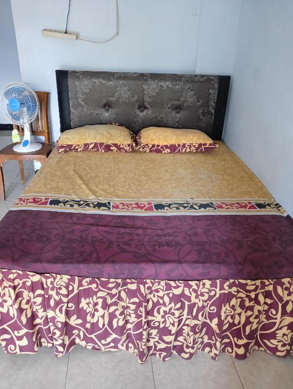 a bedroom with a bed with a purple bedspread and a fan at Bale Sasak guest house in Selaparang