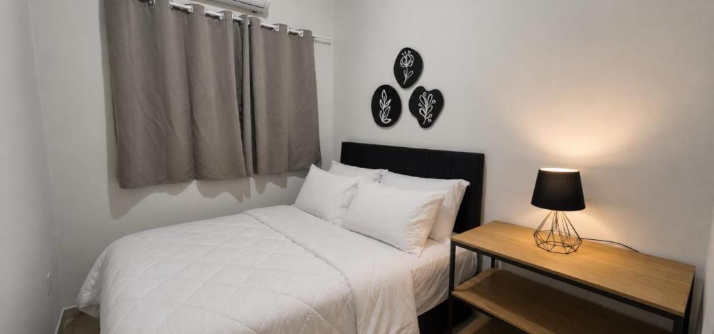 a bedroom with a white bed and a table with a lamp at Casa Harmonia - Ar Condicionado in Bom Jesus da Lapa