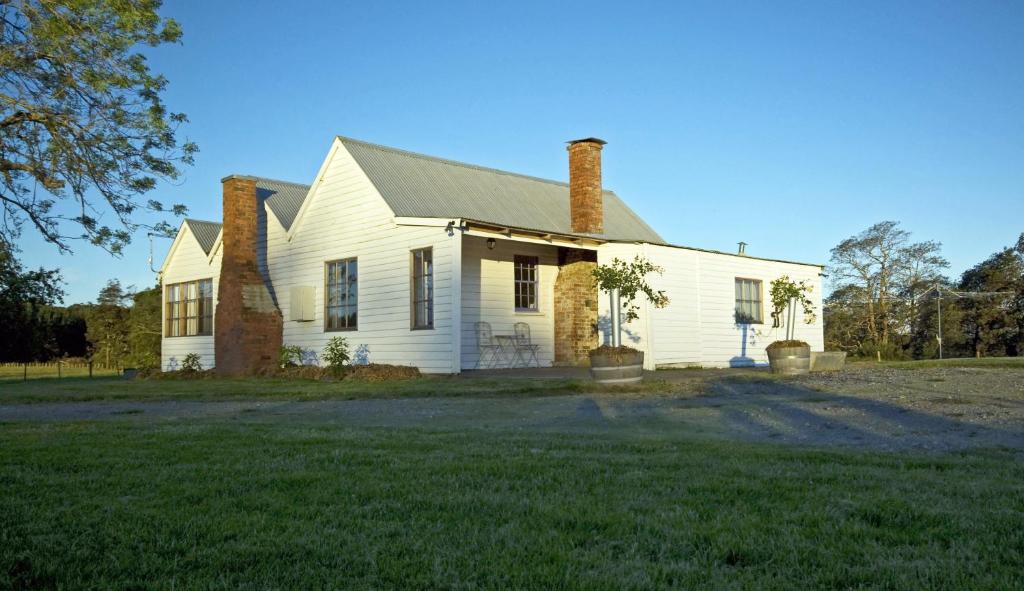 a white house with two chimneys on a yard at Buttons Cottage for a northwest Tassie escape in Nietta