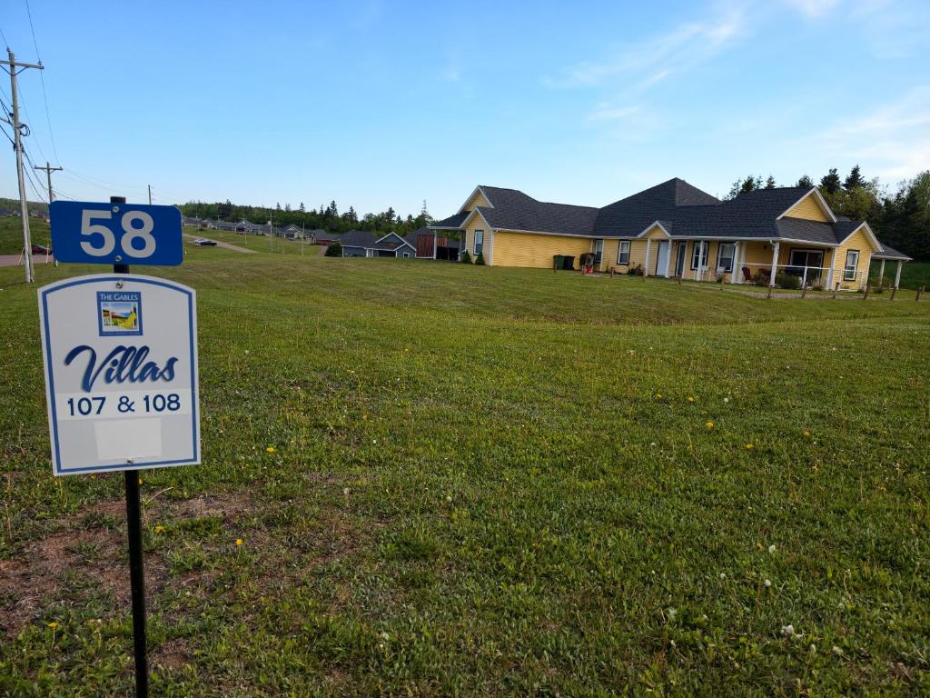 a sign in a field with a house in the background at Near Cavendish Beach-2 in Stanley Bridge