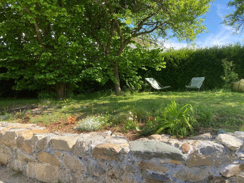 two chairs sitting in a yard next to a stone wall at Maisonnette Hauts d'Evian in Larringes