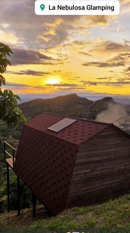 a photo of a building with the sunset in the background at La Nebulosa Glamping in Vergara