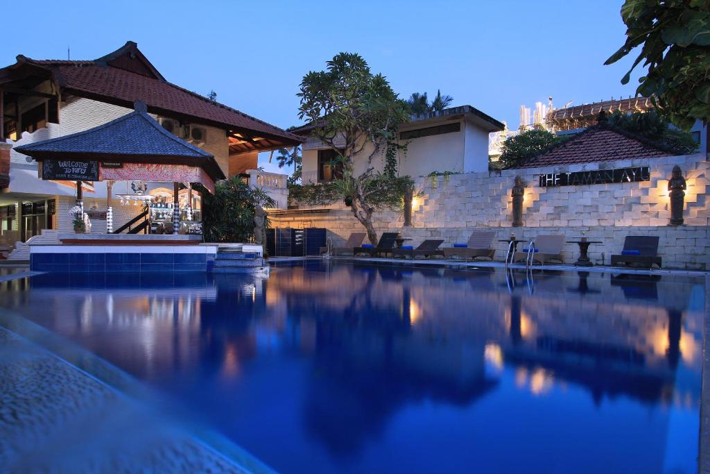 a swimming pool with chairs and a building at The Taman Ayu in Seminyak