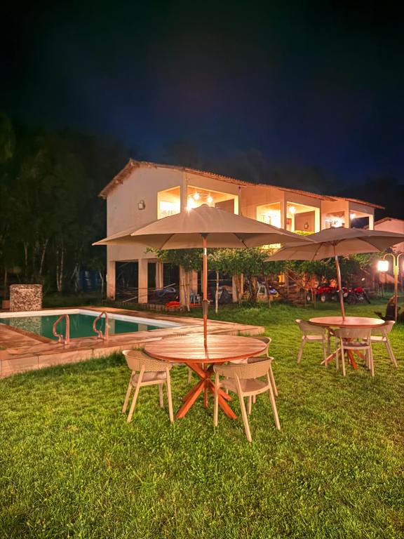 two picnic tables with umbrellas in front of a house at Rancho PJ - Presidente Juscelino-MA in Morros
