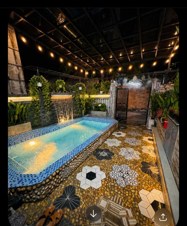 a swimming pool with umbrellas and a tile floor at Đại Nội Saphia Homestay & Villa in Hue