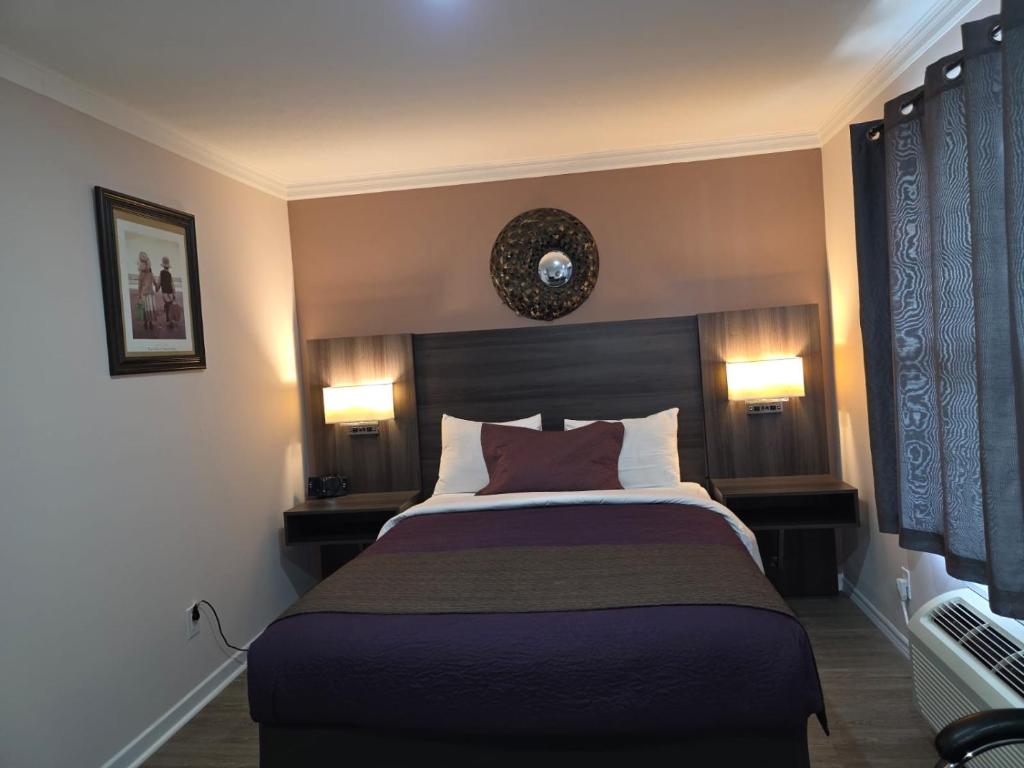 a bedroom with a large bed with two lamps on it at Lakeview Motel & Cottage in Kincardine