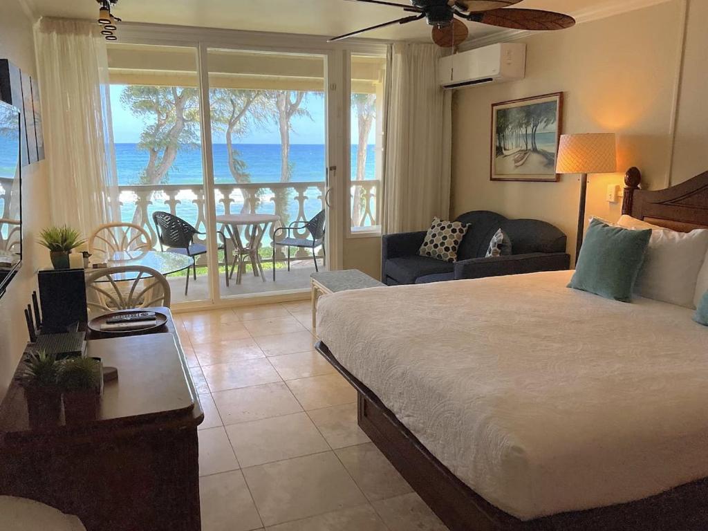 a bedroom with a bed and a view of the ocean at Oceanfront Studio at Islander on the Beach #325 in Kapaa
