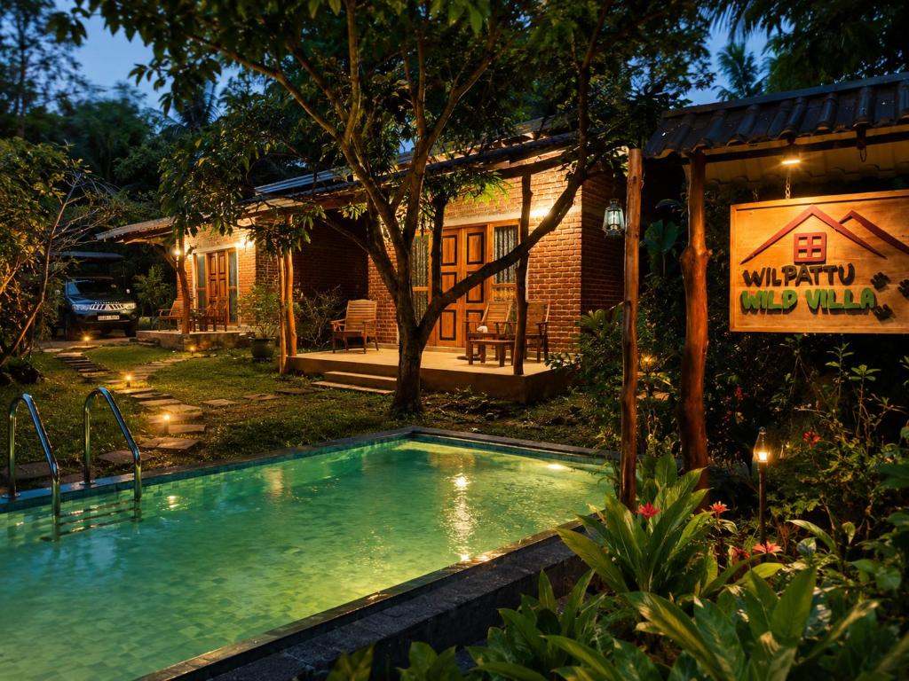 a swimming pool in front of a house at Wilpattu Wild Villa in Pahala Maragahawewa