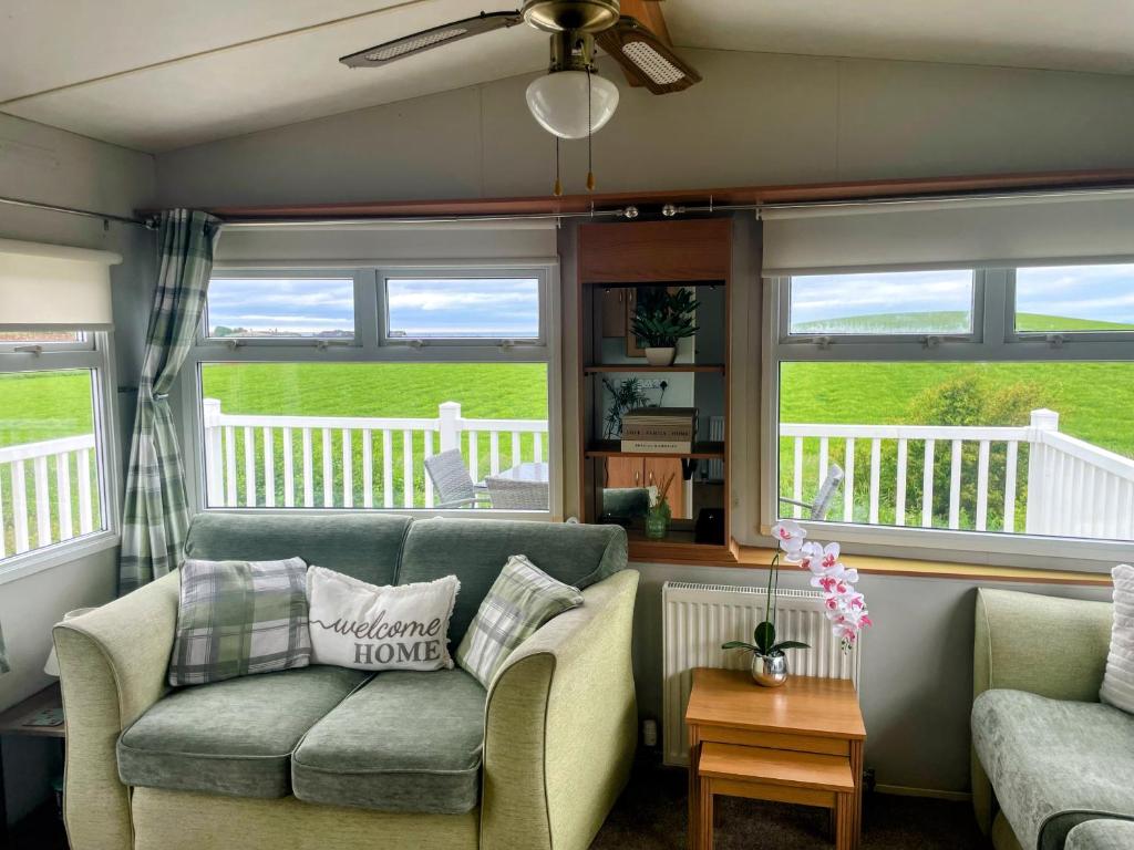 a living room with a couch and two chairs and windows at Ailsa Seaview in Turnberry