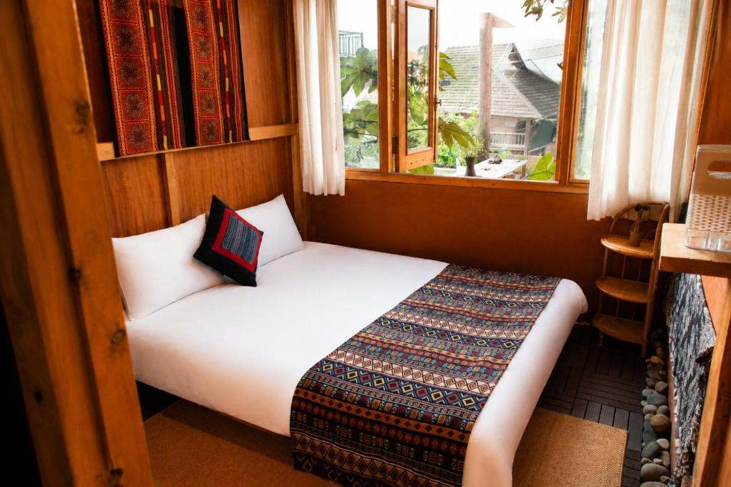 a bedroom with a bed in a room with a window at Hihi Homestay Tả Van - Mountain View & Local Experience in Sa Pa in Tả Van