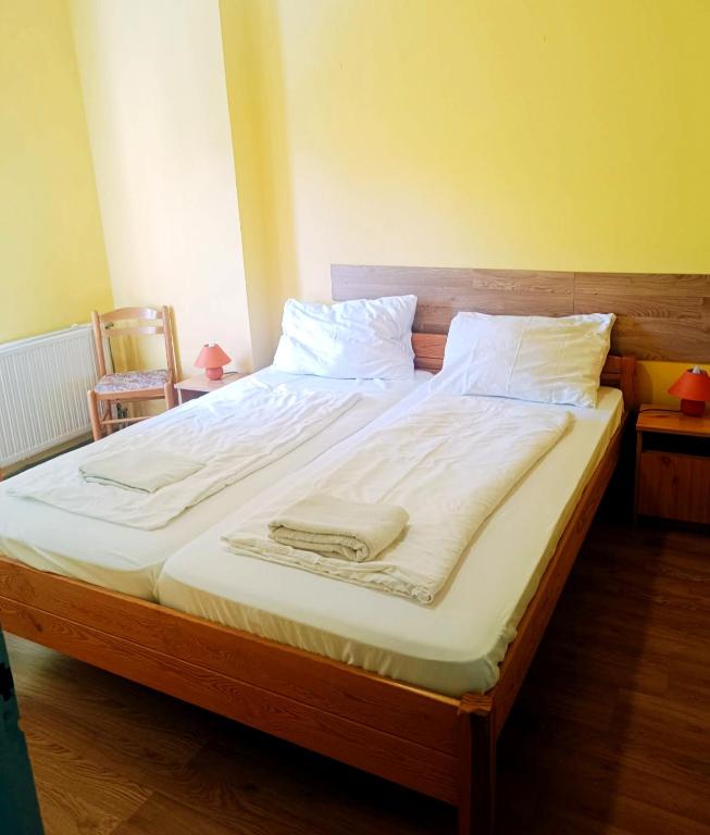 a large bed with white sheets and a towel on it at Király Szálló in Nagykanizsa