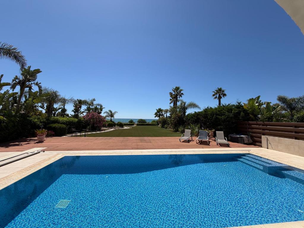 a swimming pool with two chairs and a yard at Emerald Seafront Residence in Ayia Napa