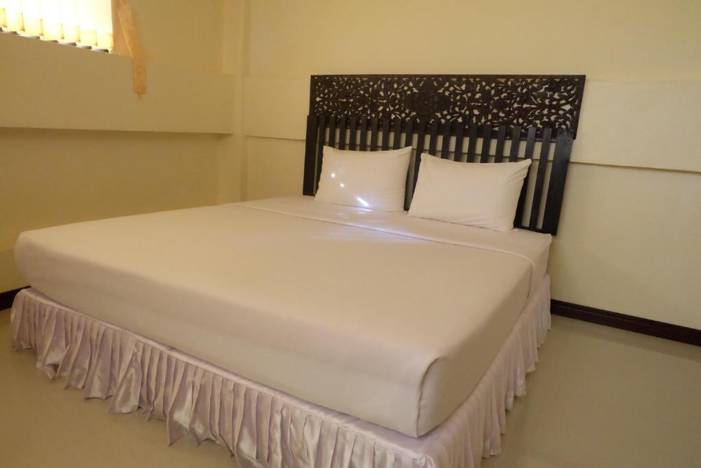 białe łóżko z czarnym zagłówkiem i białymi poduszkami w obiekcie J-Safe Guesthouse w mieście Sukhothai