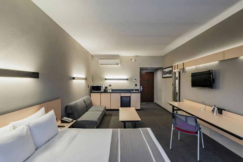 A larger room with a bed, sofa, kitchenette-style counter and dedicated desk.