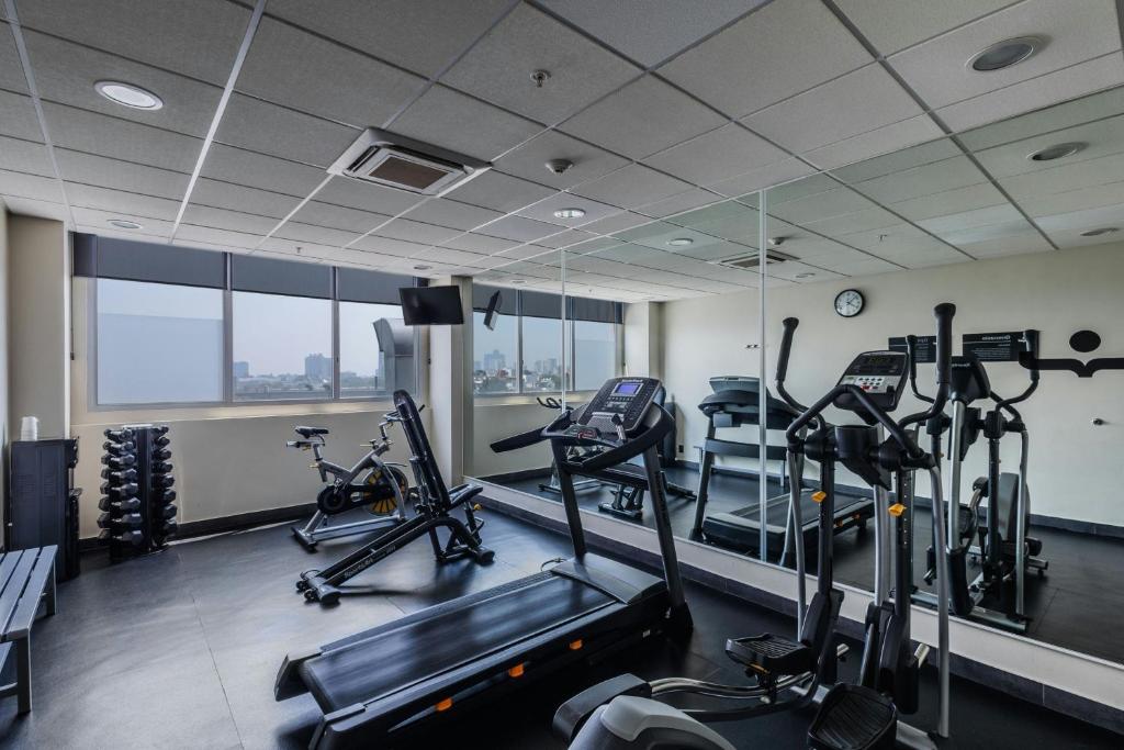A bright hotel gym with cardio machines, weights and mirrored walls.