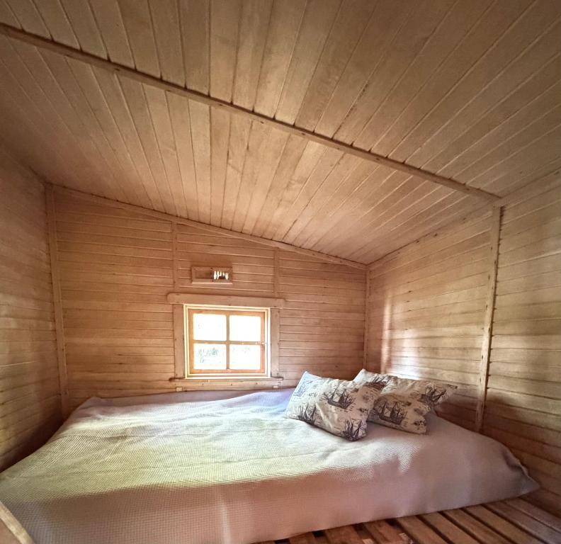 a bed in a wooden room with a window at The lake house in Mockava