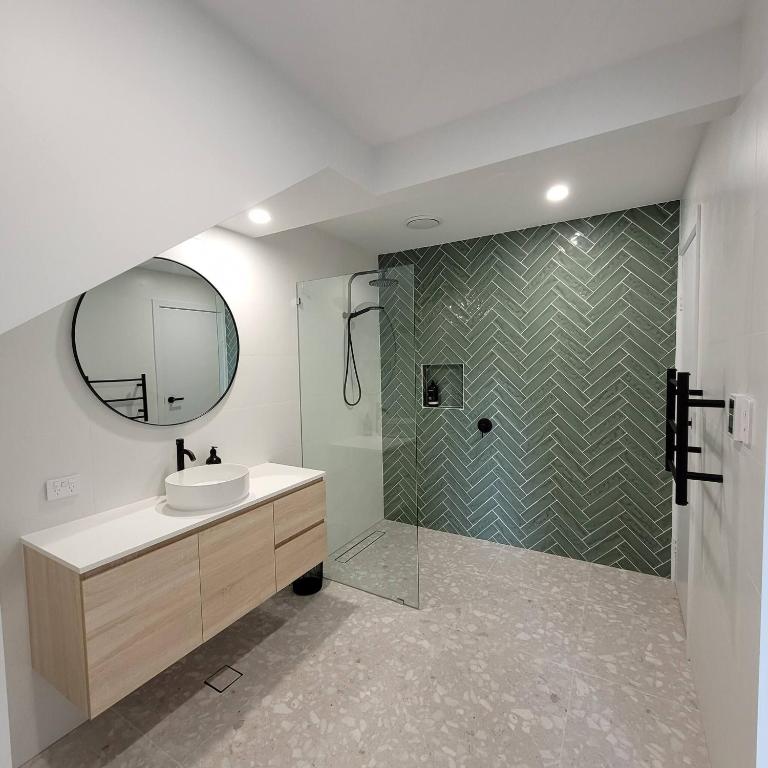 a bathroom with a sink and a shower with a mirror at Pandanus Studio Lennox Head in Lennox Head