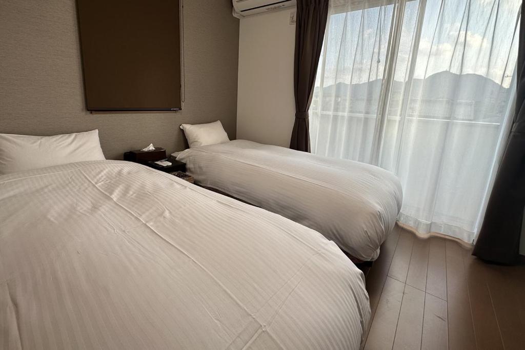 zwei Betten in einem Hotelzimmer mit Fenster in der Unterkunft 萩別邸 シーサイド2 HAGI Bettei SEASIDE2 in Hagi