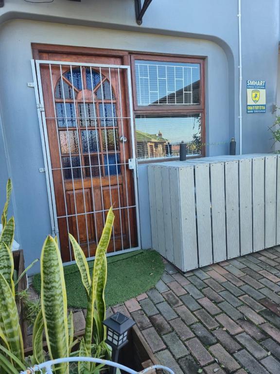a house with a wooden door and a fence at At Lilac Cottage, Jeffreys Bay Cozy stay for 2 & Business traveling in Jeffreys Bay