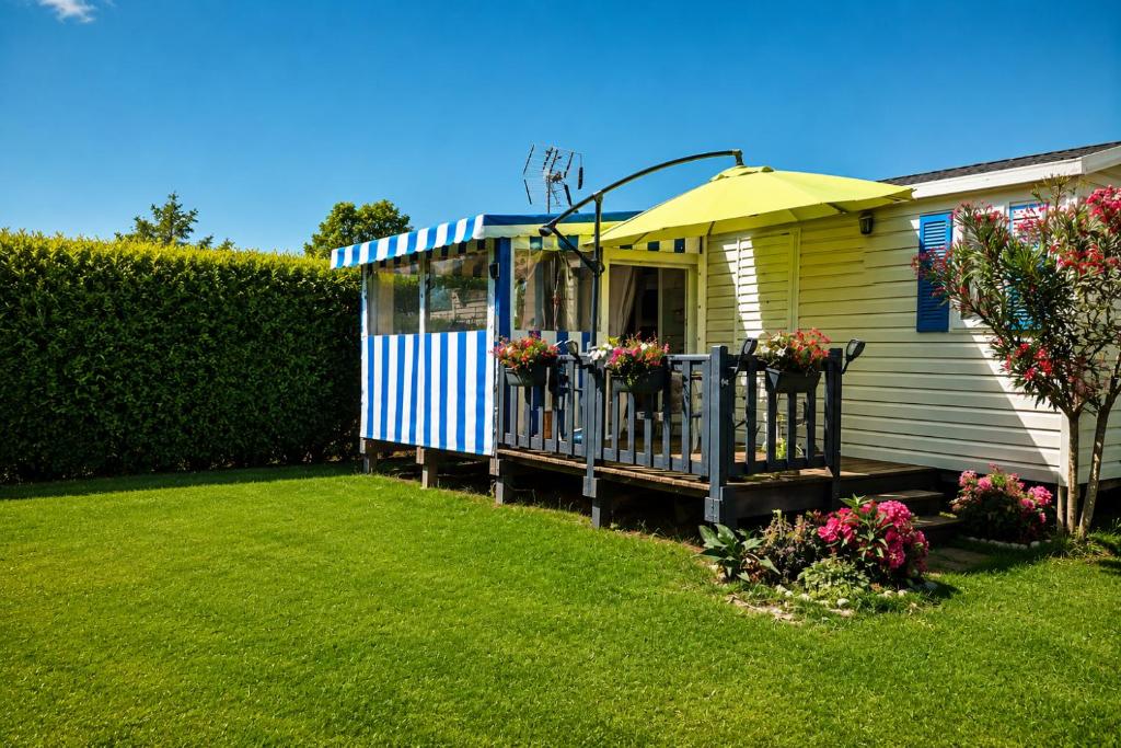 a small yellow and blue house with a porch at Omaha beach mobilhome in Colleville-sur-Mer