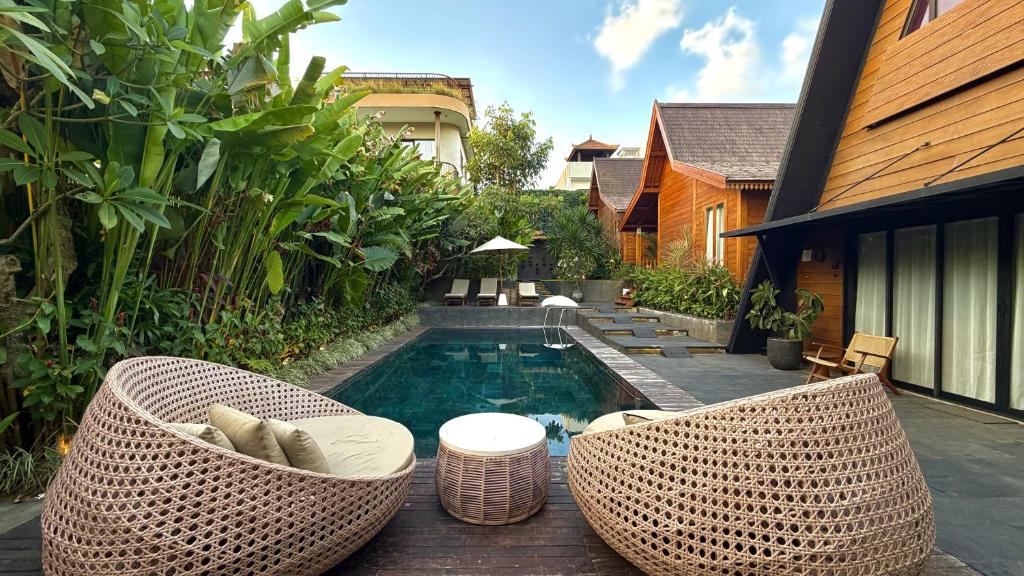a backyard with a swimming pool with wicker chairs at Twinseas Villa in Uluwatu