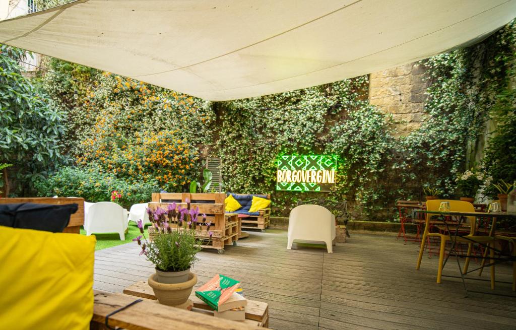a patio with tables and chairs and a wall of plants at Borgo Vergini Garden B&B in Naples